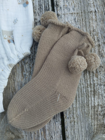 Calcetines con pompones en un elegante color Tostado perfectos para mantener a los pequeños abrigados y con estilo durante los días fríos. Perfectos para combinar con la colección buhos