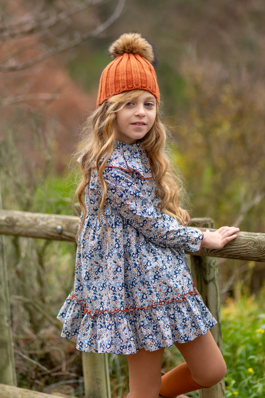 Vestido Marina de Boetiekids con flores azules y cuello con volante ribeteado en color caldera con vuelo y rematado con gran volante en la parte inferior
