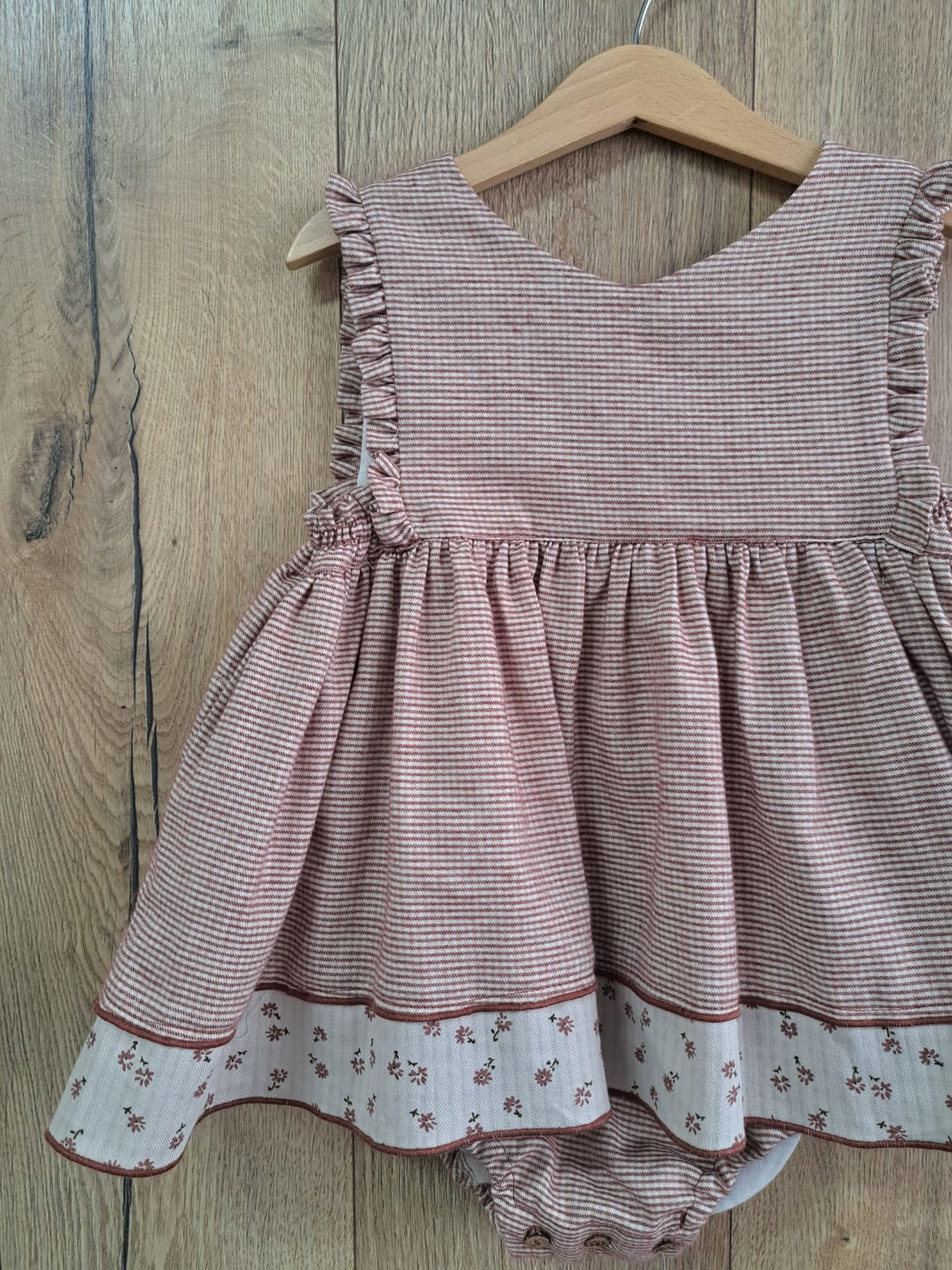 Ranita Telva de Boetiekids, en vichy color teja oscuro con tirante ancho y rematada en los costados con volantito, en la parte inferior lleva franja de tela de florecitas y braguita a juego. Ideal para combinar con la blusa Telva