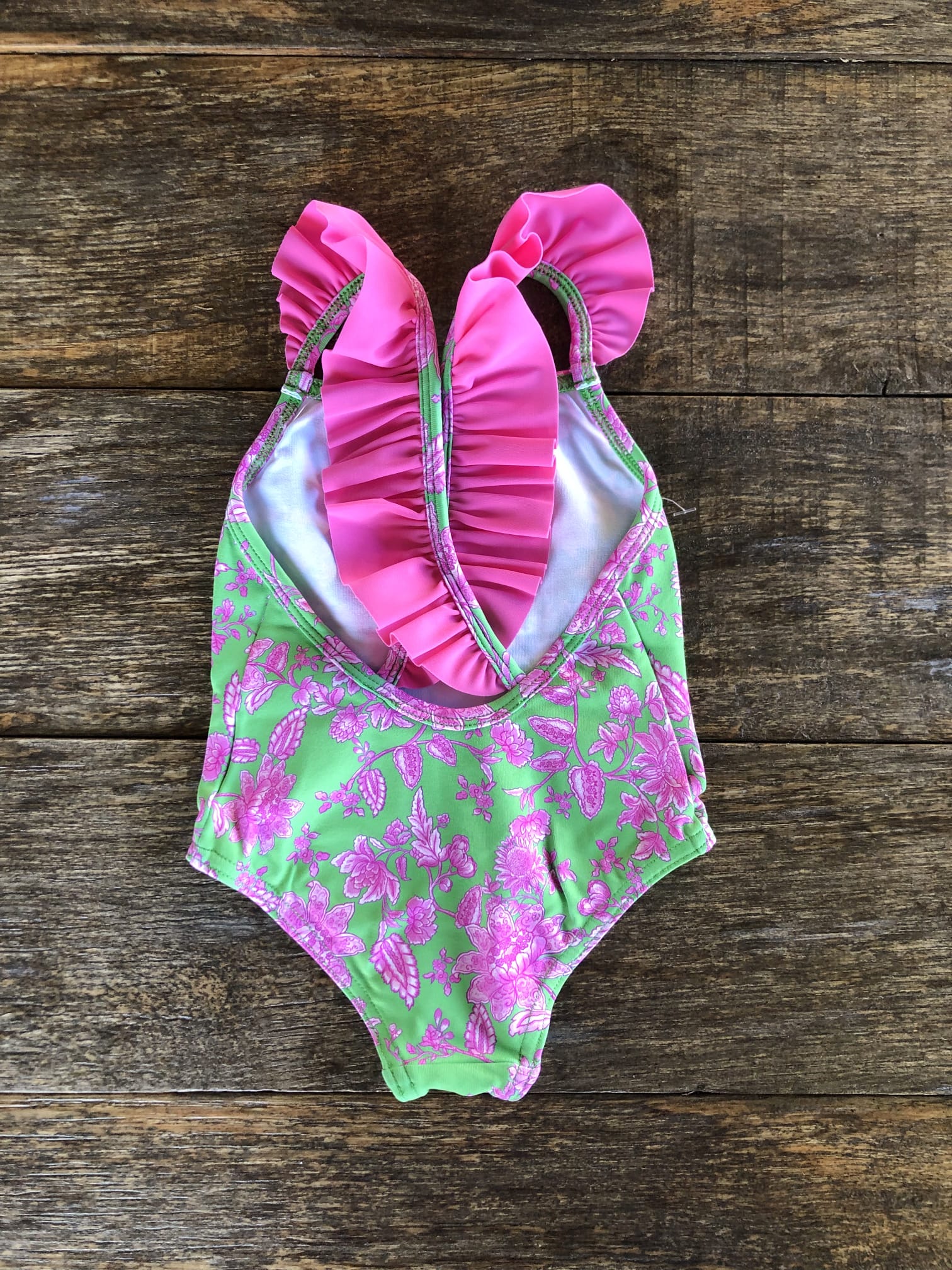Bañador para niña en color verde con flores color fuxia y volante a juego en los tirantes