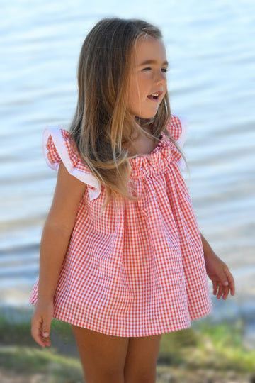 Blusa vichy Lili de Boetie kids, en color coral y blanco, sin mangas, de pierna corta, abrochada en el delantero con botones de madera y cintura elástica.