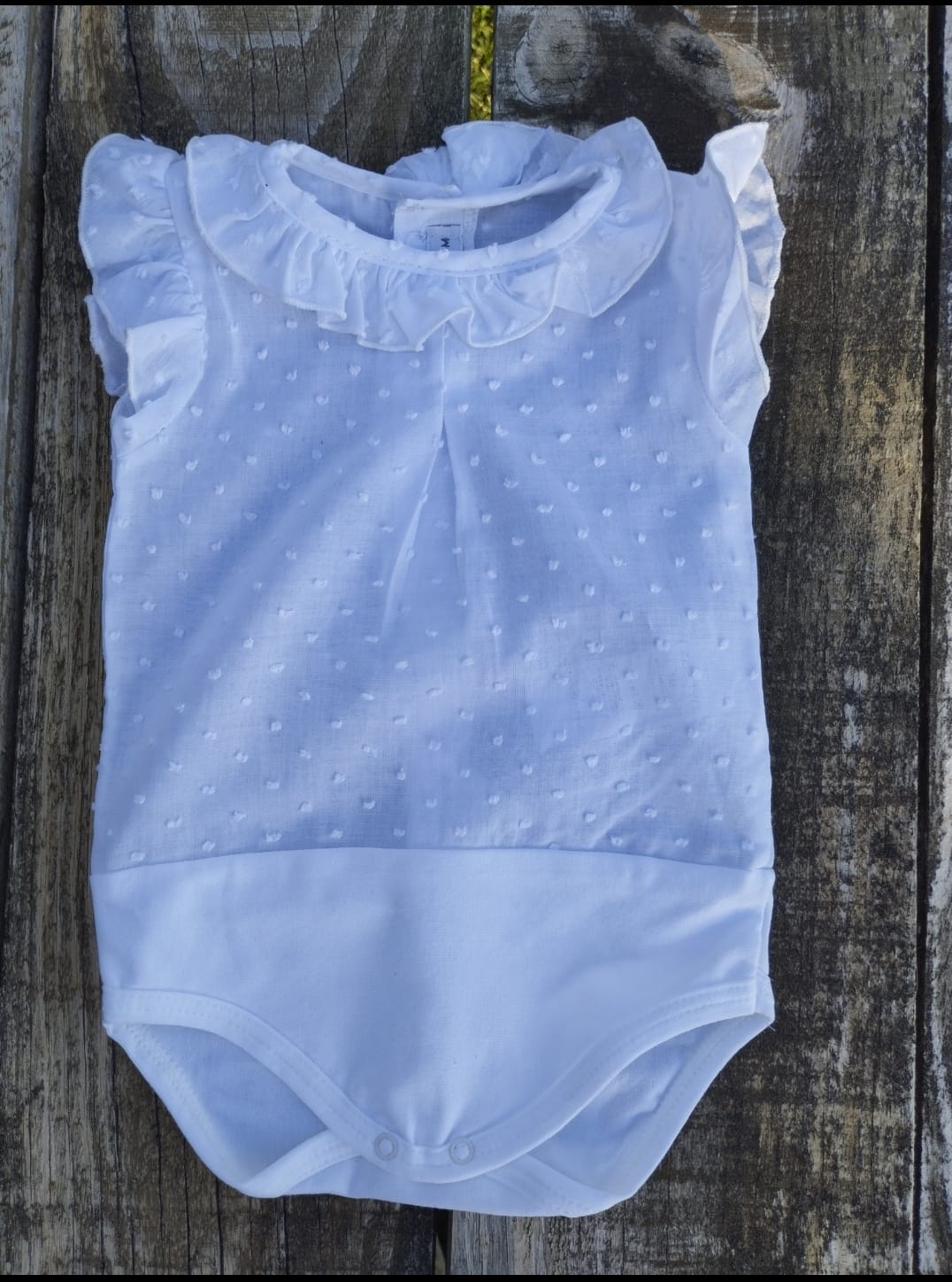 body camisa sin mangas de plumeti en color blanco, va abotonado en la espalda y con abertura en la entrepierna para facilitar el cambio de pañal.