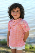 Camisa vichy niño Lili, en color coral y blanco de manguita corta y abrochada en el delantero con dos botones de madera.