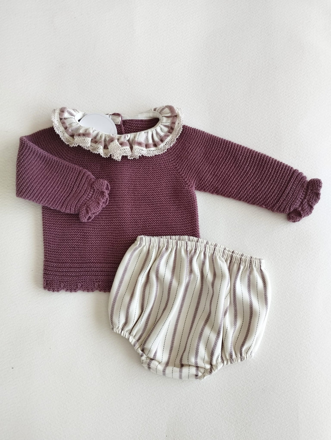 conjunto de jersey en punto color berenjena abotonado en la espalda con cuellito de volante a juego con pololo de rayas a tono.