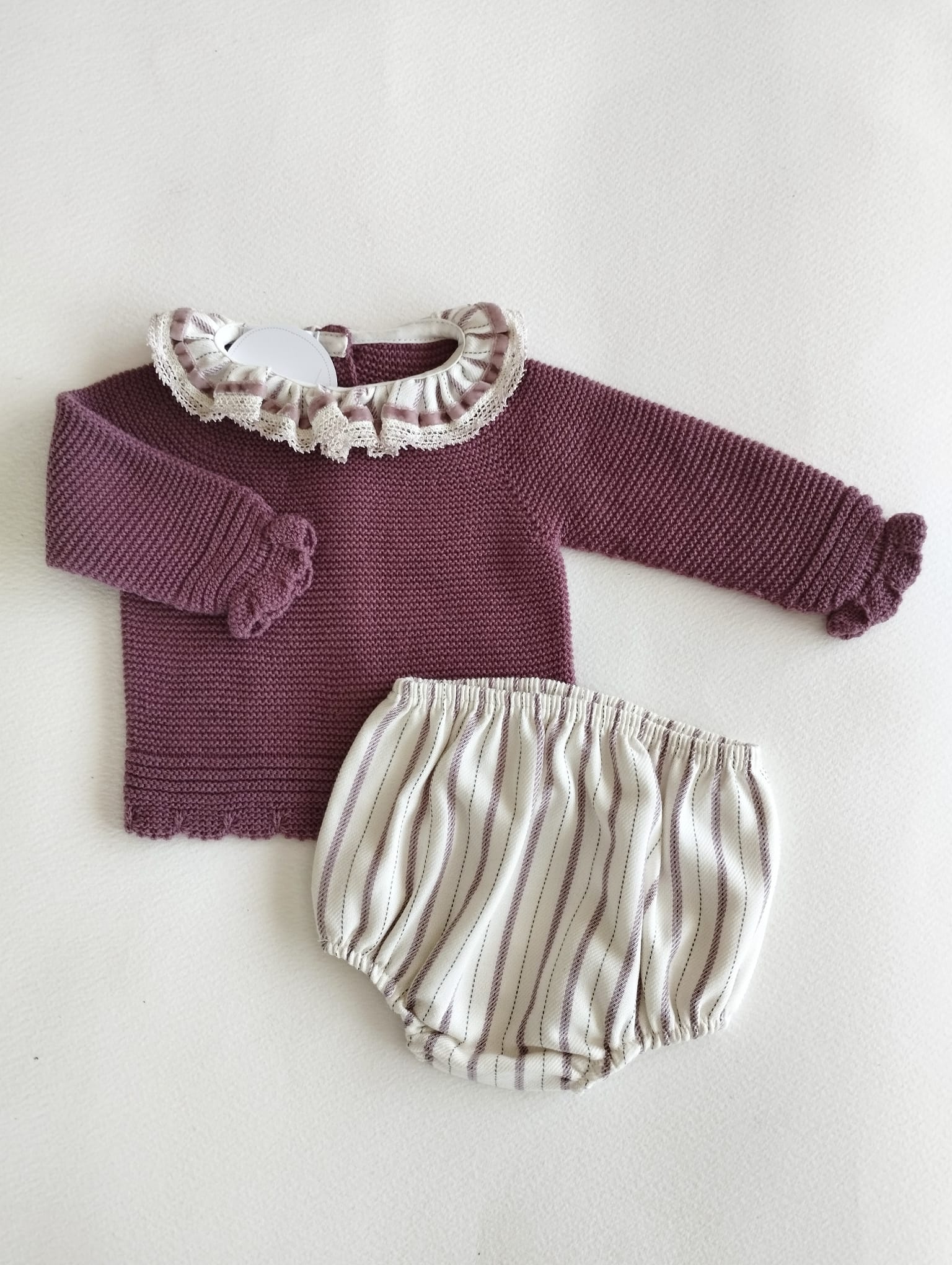 conjunto de jersey en punto color berenjena abotonado en la espalda con cuellito de volante a juego con pololo de rayas a tono.