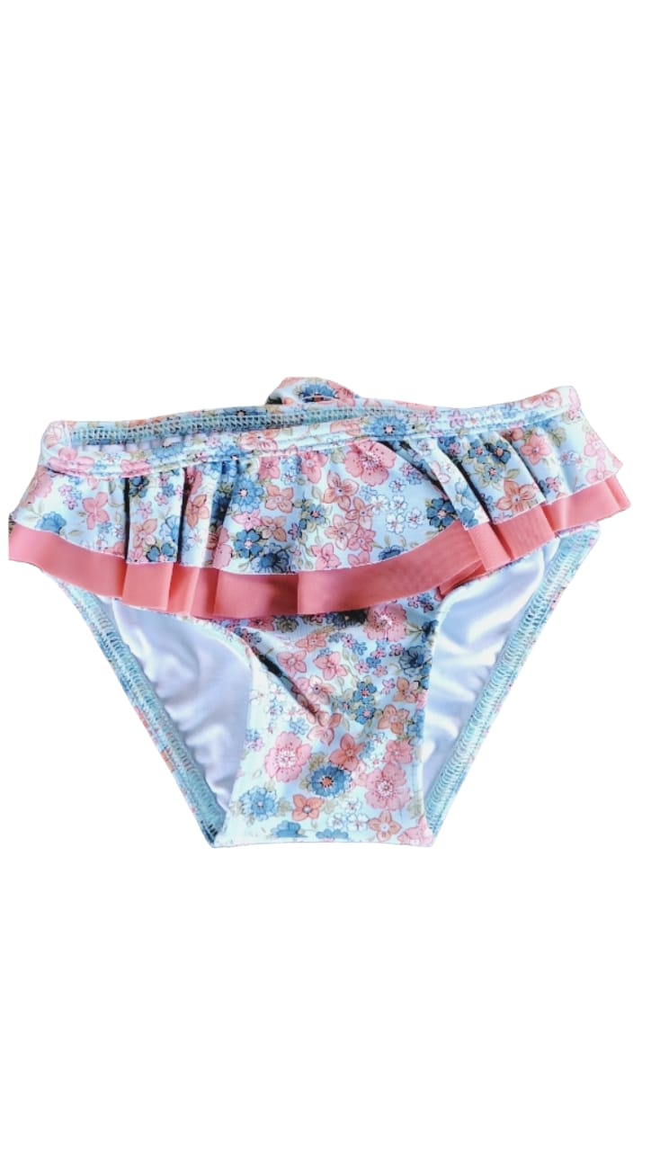 bañador culetín coral para niña con florecitas azules, coral y blancas sobre fondo azul claro, con volante coral