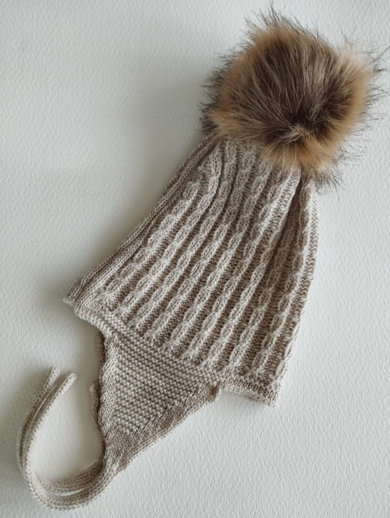 Mantén a tu peque abrigado y adorable con este gorro de punto en color arena. Su diseño con orejeras protege del frío y se ajusta cómodamente, asegurando que las orejitas estén siempre calentitas.