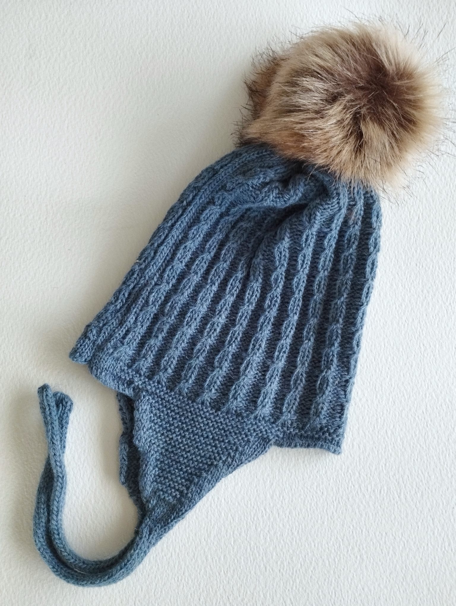 Mantén a tu peque abrigado y adorable con este gorro de punto en color Azul plomoo. Su diseño con orejeras protege del frío y se ajusta cómodamente, asegurando que las orejitas estén siempre calentitas.