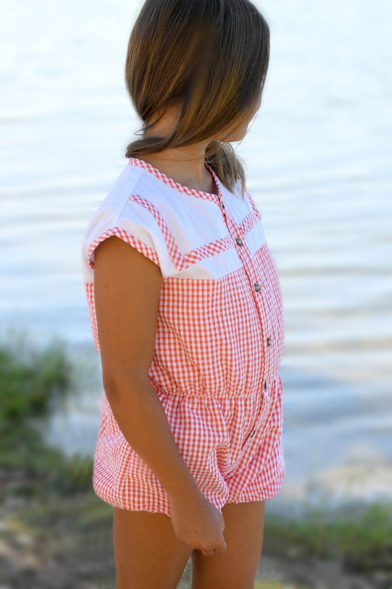 Mono vichy lili de Boetie kids en color coral y blanca, sin mangas de pierna corta abrochado en delantero con botones de madera y cintura elástica.
